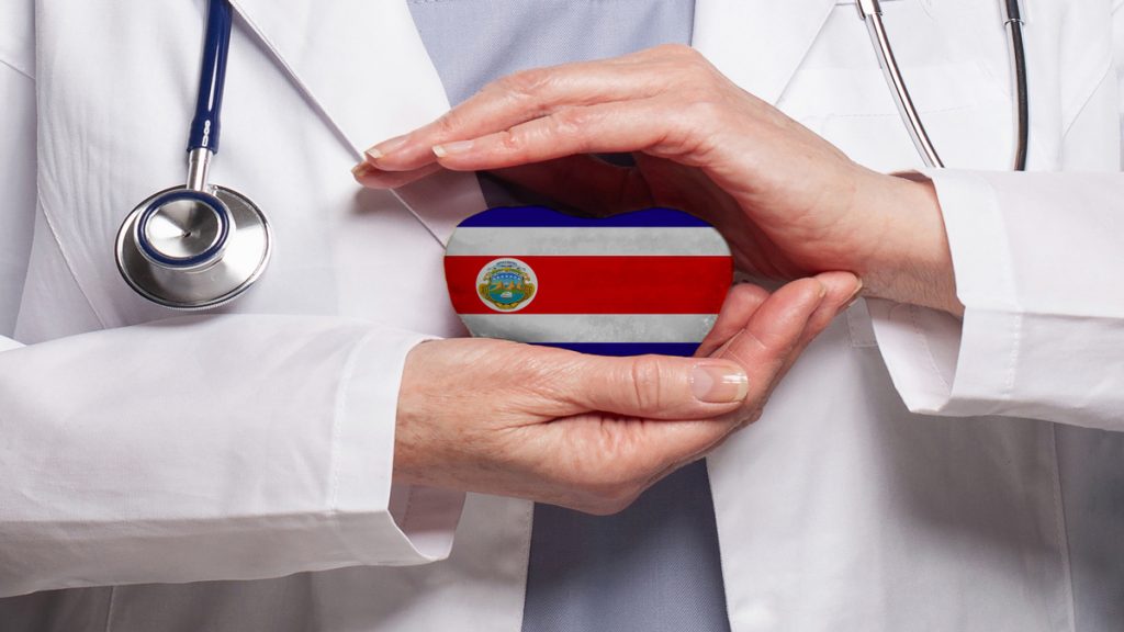 Doctor sujetando un corazón con la bandera de Costa Rica entre sus manos